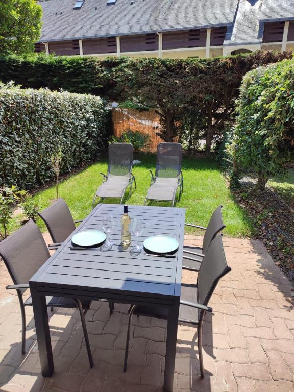 une table bleue avec des chaises et une bouteille dessus dans l'établissement Charmant appartement T2, RDC à Carnac à 200m de la plage avec jardin et terrasse, à Carnac