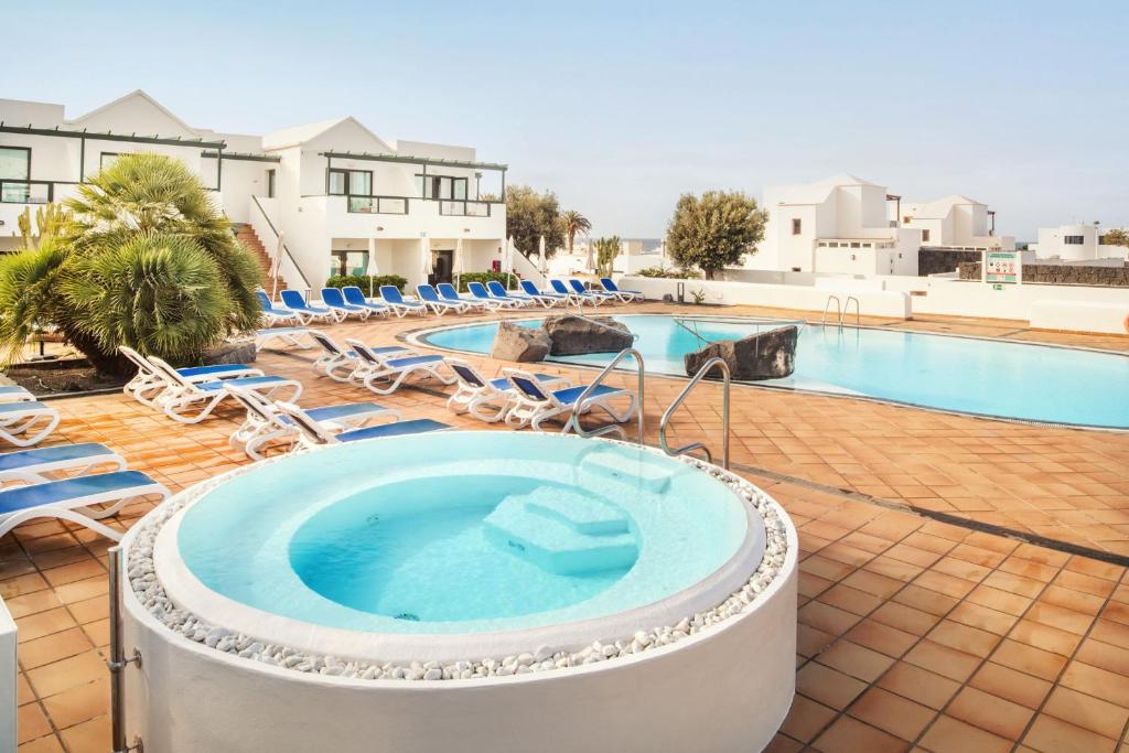 a pool with a hot tub and lounge chairs at Hotel Pocillos Playa, solo Adultos in Puerto del Carmen