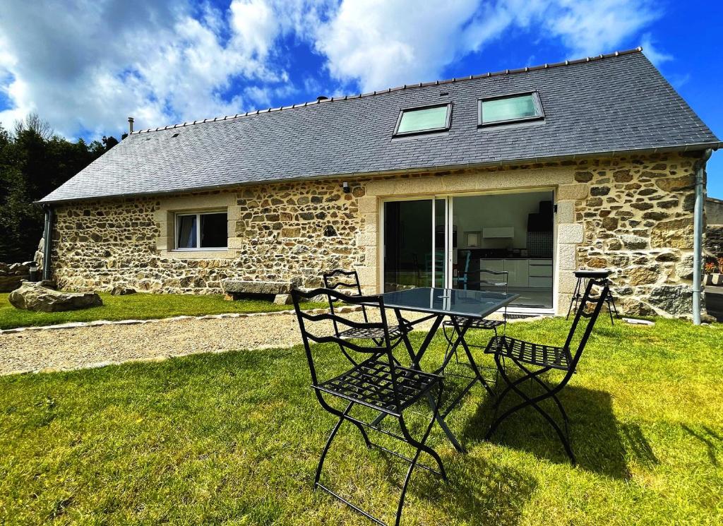 a table and chairs in front of a stone house at Maison Le Rohel. in Pleubian
