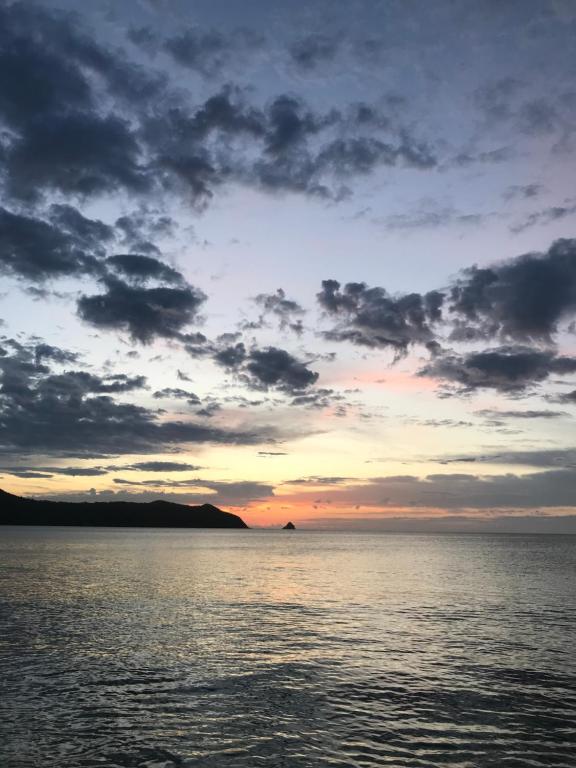 a sunset over the water with a cloudy sky at 檸檬草ー奄美の自然の香る宿ー in Amami