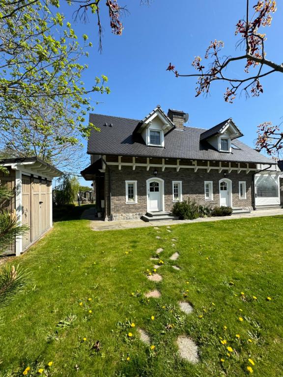ein Haus mit einem grünen Rasen davor in der Unterkunft Bay Cottage wynajem domków in Swarzewo