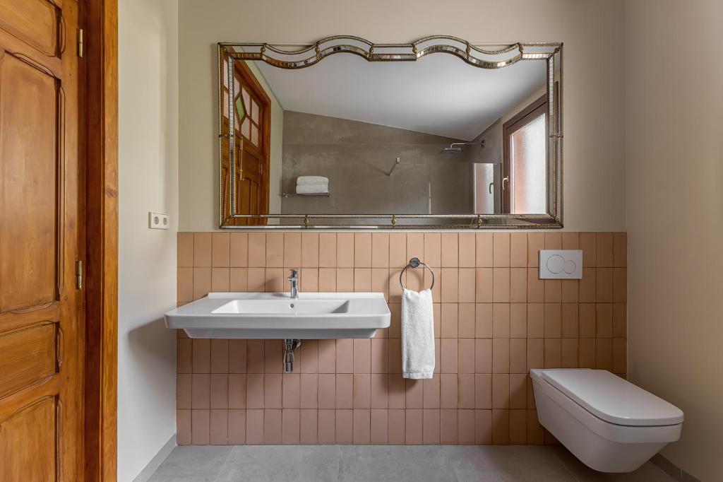 een badkamer met een wastafel, een toilet en een spiegel bij La Novieta Boutique Hotel - Adults Only in Valencia