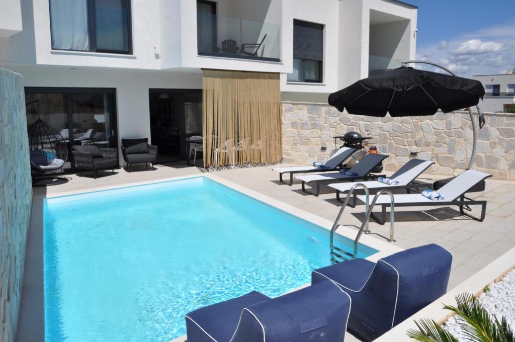 a swimming pool with chairs and an umbrella at Lemon Navy house in Vodice