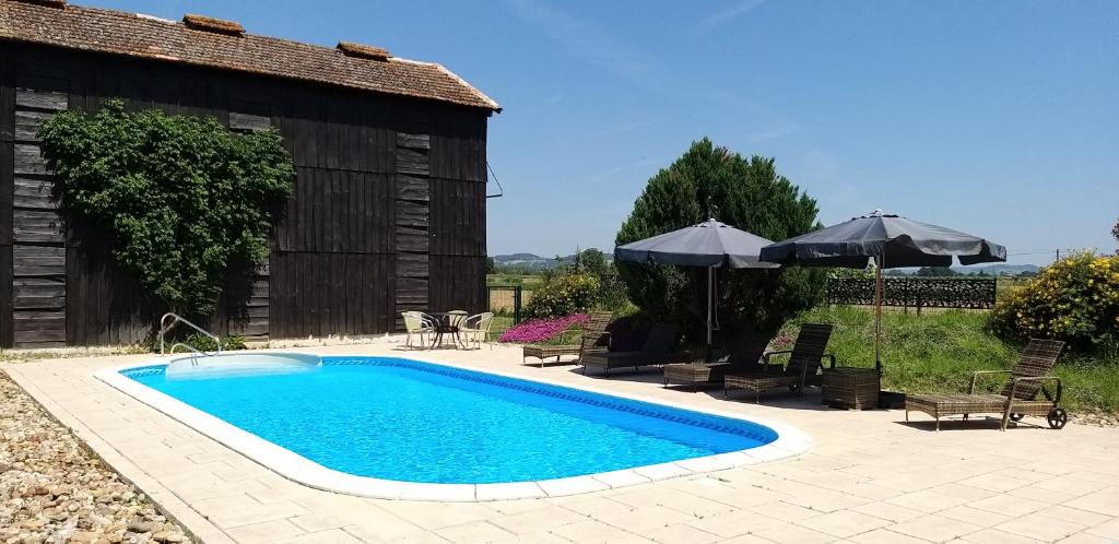 une piscine avec chaises et parasols à côté d'un bâtiment dans l'établissement Hortensia & Rose Gites, à Montpezat
