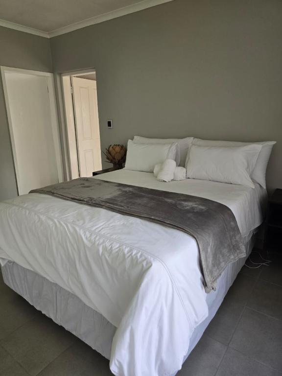 a large bed with white sheets and pillows at Airport Fresh Lodge in Boksburg