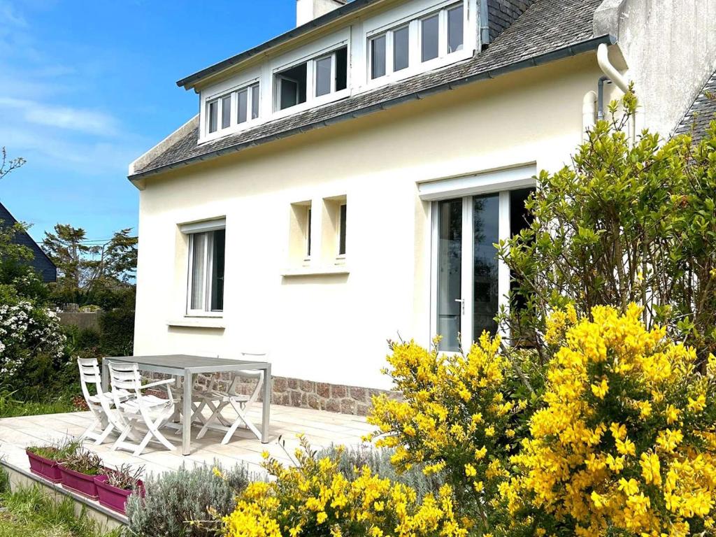 Cette maison blanche dispose d'une terrasse avec une table et des chaises. dans l'établissement Charmante maison rénovée à Trébeurden avec jardin clos, terrasse et parking, à 1km de la mer - FR-1-368-423, à Trébeurden