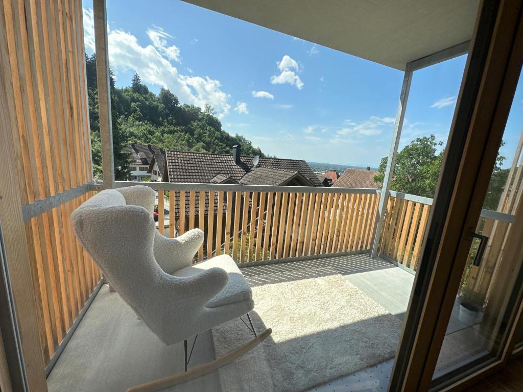 een balkon met twee witte stoelen op een veranda bij Bodenseeblick Dornbirn in Dornbirn