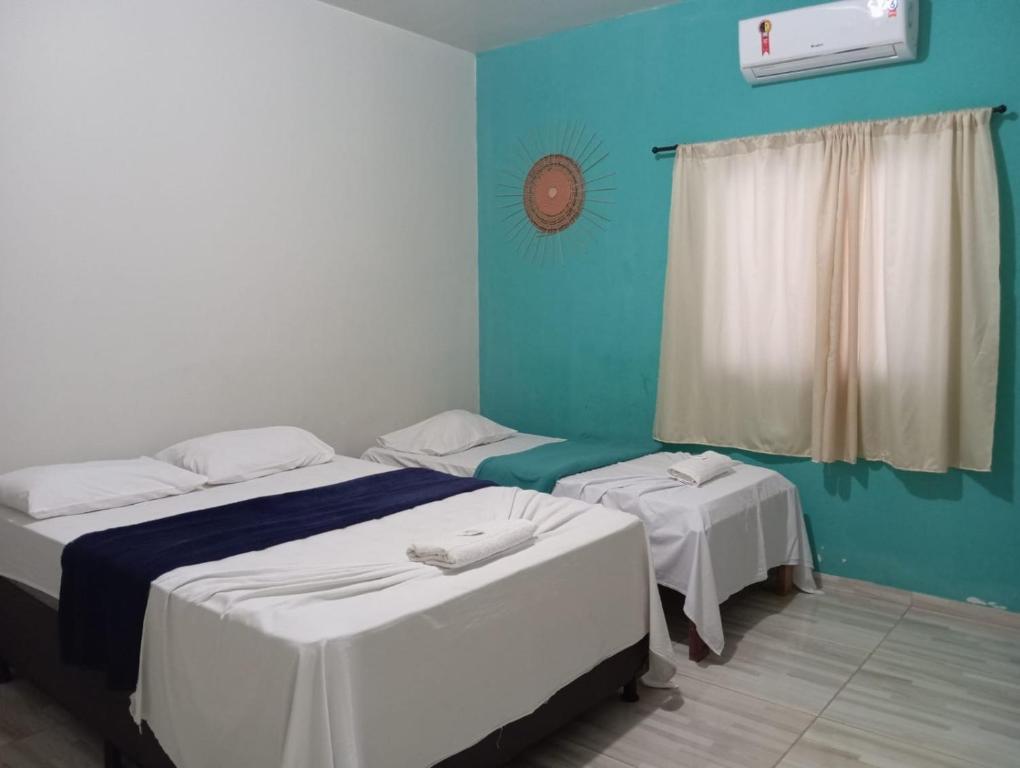 two beds in a room with blue walls and a window at Hotel Lajeado in Lajeado