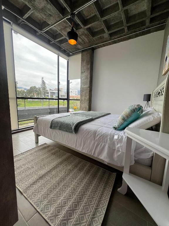 a bedroom with a bed and a large window at Tinta & hierro suite 1 in Loja