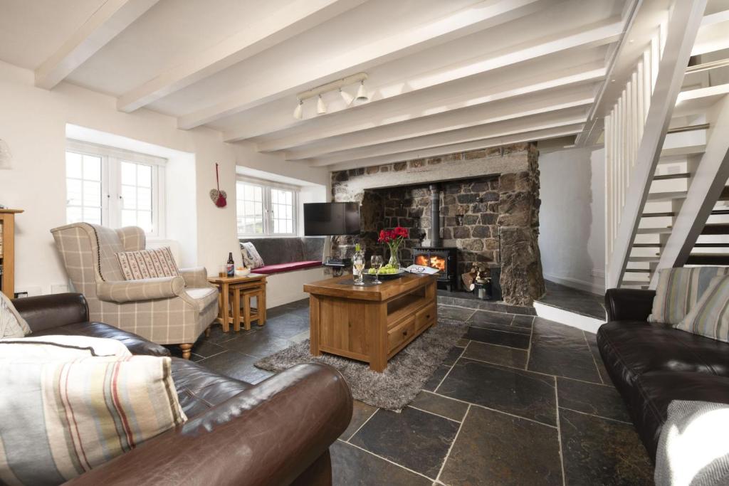 un salon avec un canapé et une cheminée dans l'établissement Dolor Cottage, à Coverack