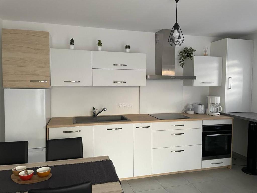 - une cuisine avec des placards blancs, un évier et une table dans l'établissement le Natural, à Thonon-les-Bains