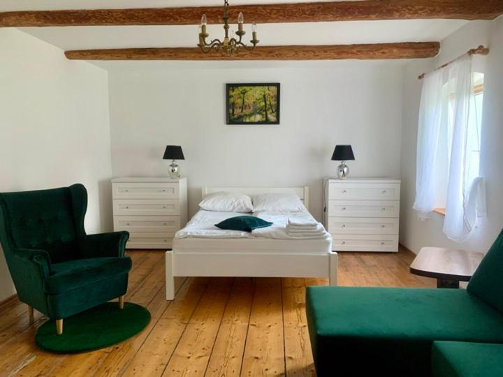 1 dormitorio con 1 cama blanca y 1 silla verde en Willa Pod Dębem en Koczarki