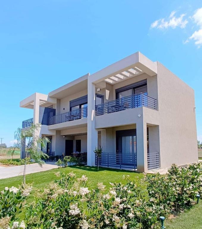 a large house with blue balconies on a lawn at Nostos Suites in Kourouta