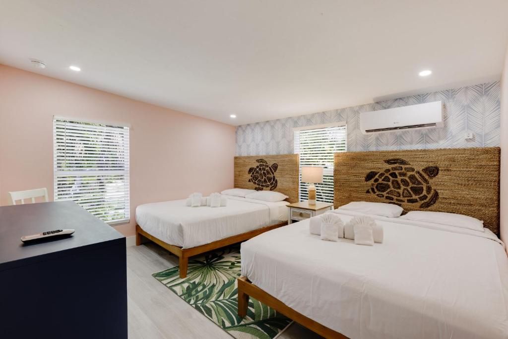 a bedroom with two beds and a desk and windows at Charming Suite with Balcony and Bikes at Historic Sandpiper Inn in Sanibel
