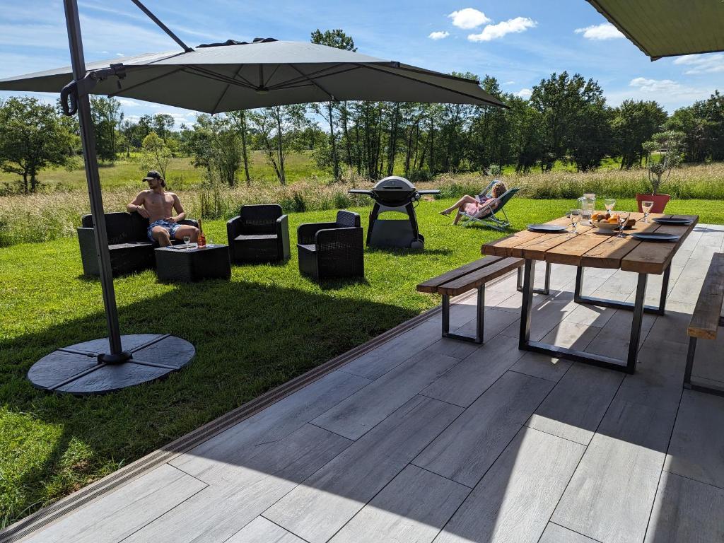 patio ze stołem, parasolem i sprzętem do grillowania w obiekcie Gite les Caravottes 4 Etoiles avec Jacuzzi - JURA w mieście Courlaoux