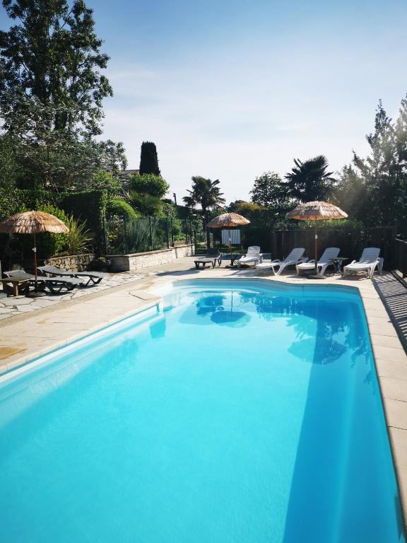 une grande piscine bleue avec chaises et parasols dans l'établissement Domaine L'Amourie Sud Ardèche, à Saint-Étienne-de-Fontbellon