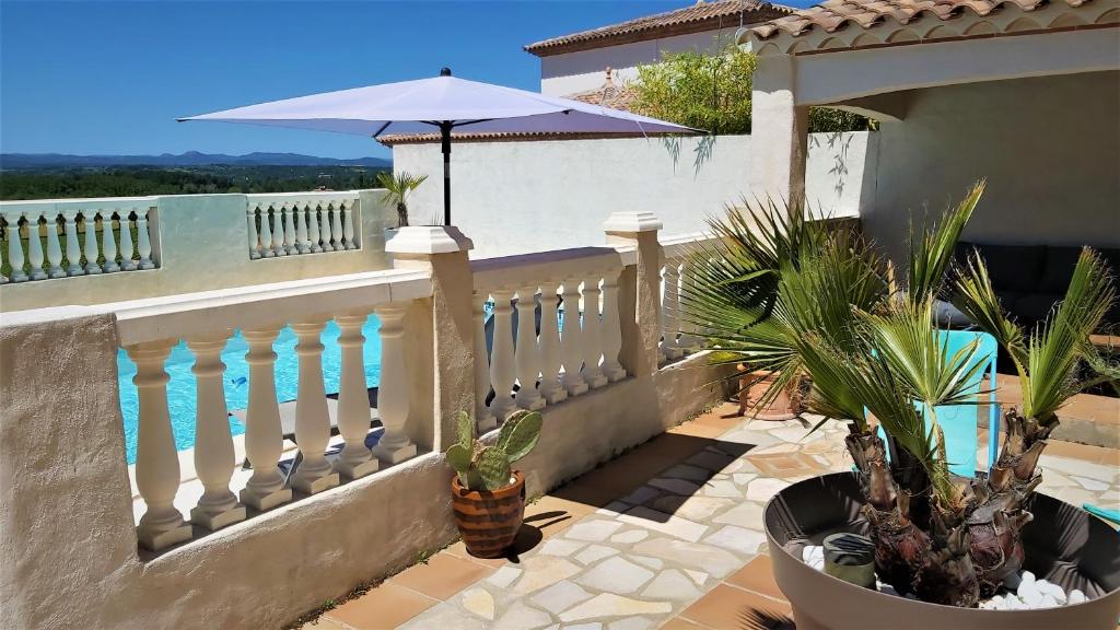 un balcon d'une maison avec un parasol et des plantes dans l'établissement Logement indépendant, piscine, pool-house et terrasse privés, à Castelnau-de-Guers