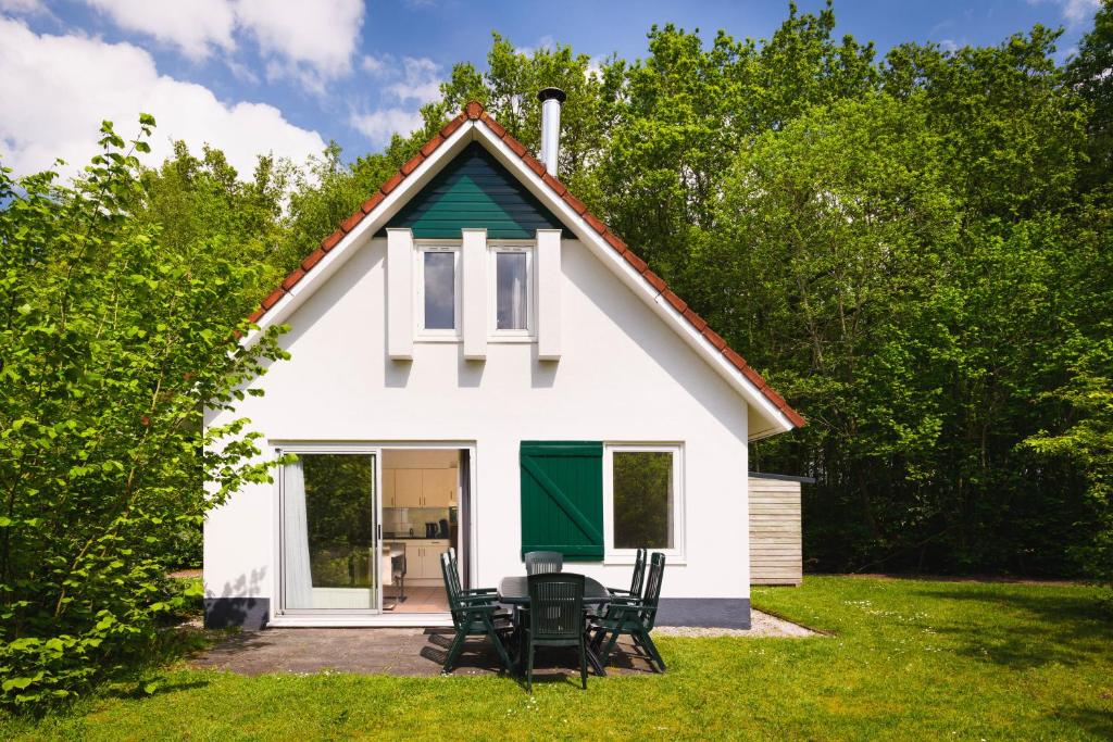 a small white house with chairs in the yard at Summio Vakantiepark Het Drentse Wold in Hoogersmilde