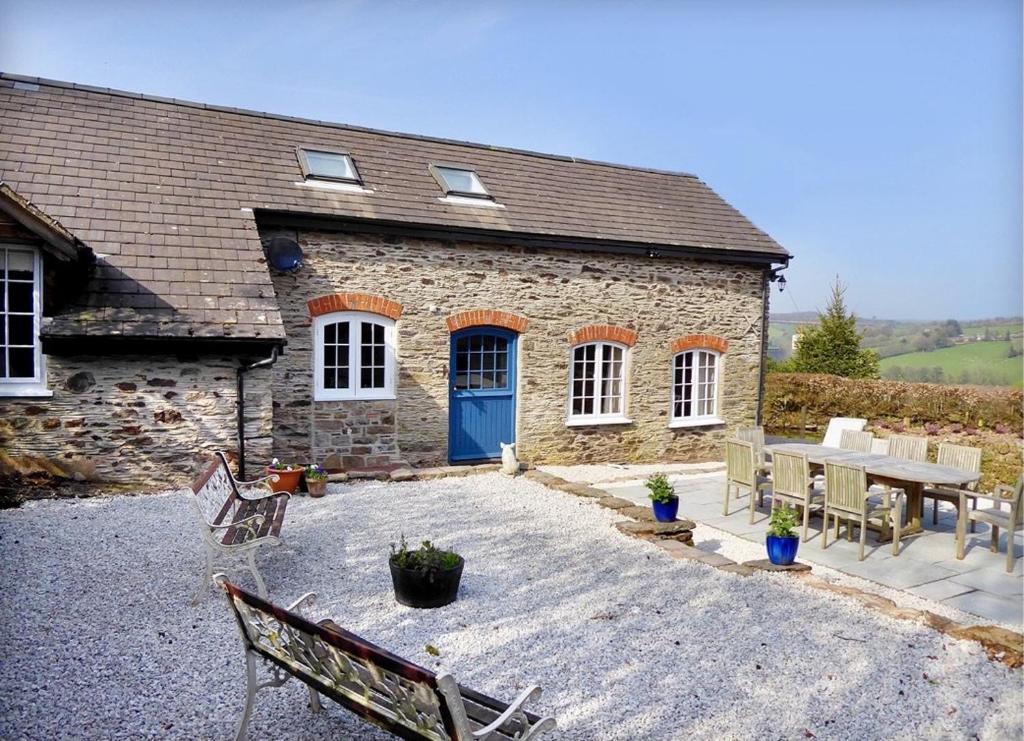 a brick house with a blue door and a patio at The Piggery, Dulverton in Dulverton