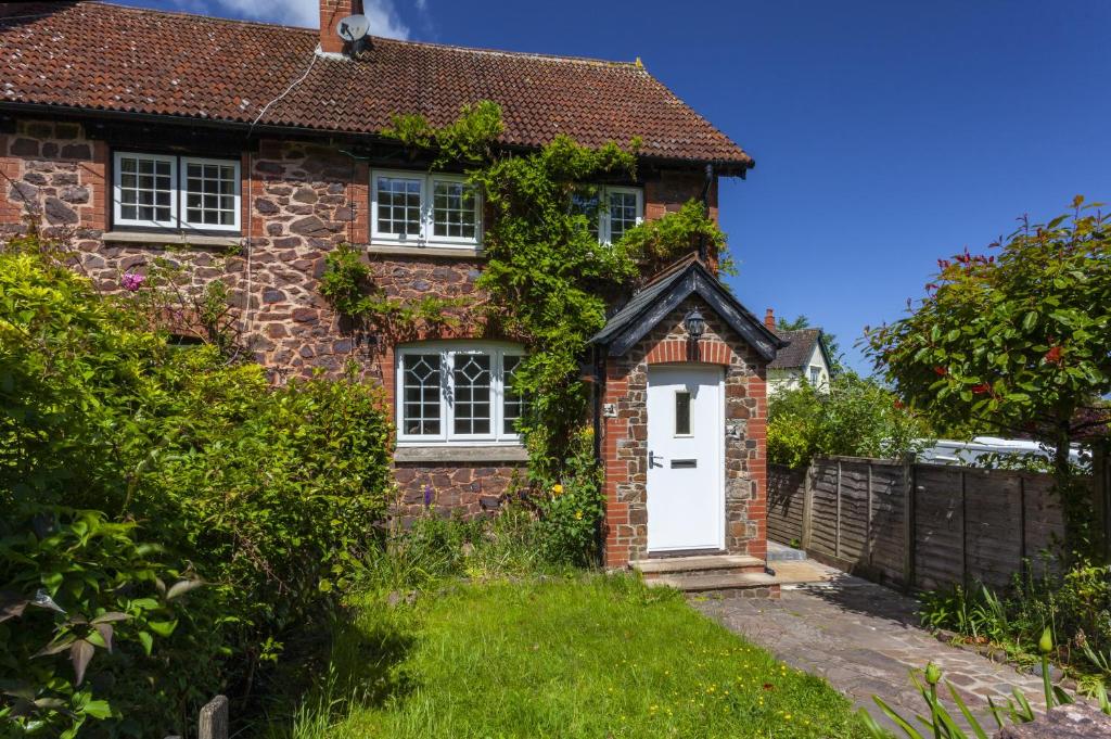 a red brick house with a white door at Jasmine Cottage Porlock in Porlock