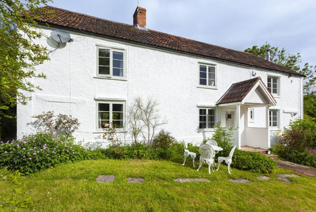 a white house with two chairs in the yard at Trinity Cottage, Roadwater in Nettlecombe