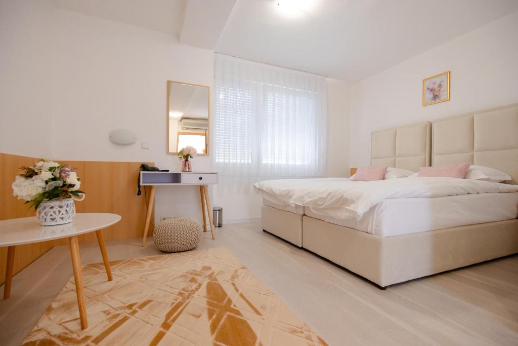 Un dormitorio blanco con una cama grande y una mesa en Hotel Panonija, en Sisak