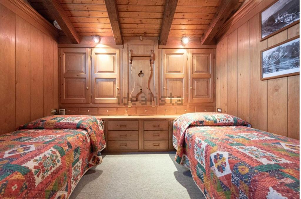 two beds in a room with wooden walls at San vito di Cadore centro - Cortina D'ampezzo in San Vito di Cadore