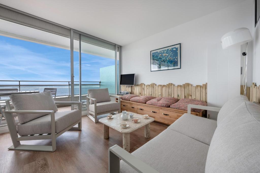 a living room with a couch and chairs and a television at Appartement pour 6, vue mer à 40m de la plage in La Baule