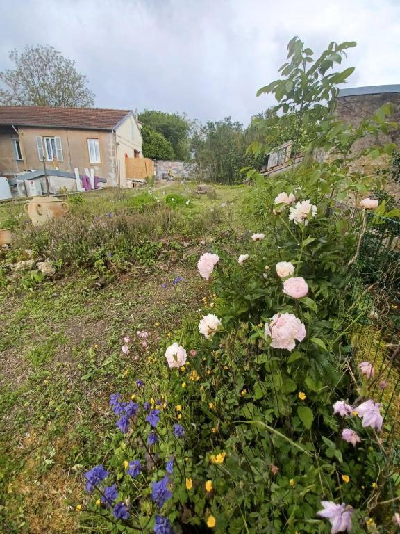 un jardin avec des roses roses et d'autres fleurs dans l'établissement Logis des Pivoines, à Trézelles