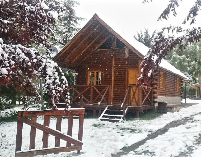 a log cabin with a snow covered porch and a fence at CABAÑA EN EL MANZANO HISTORICO in Los Árboles