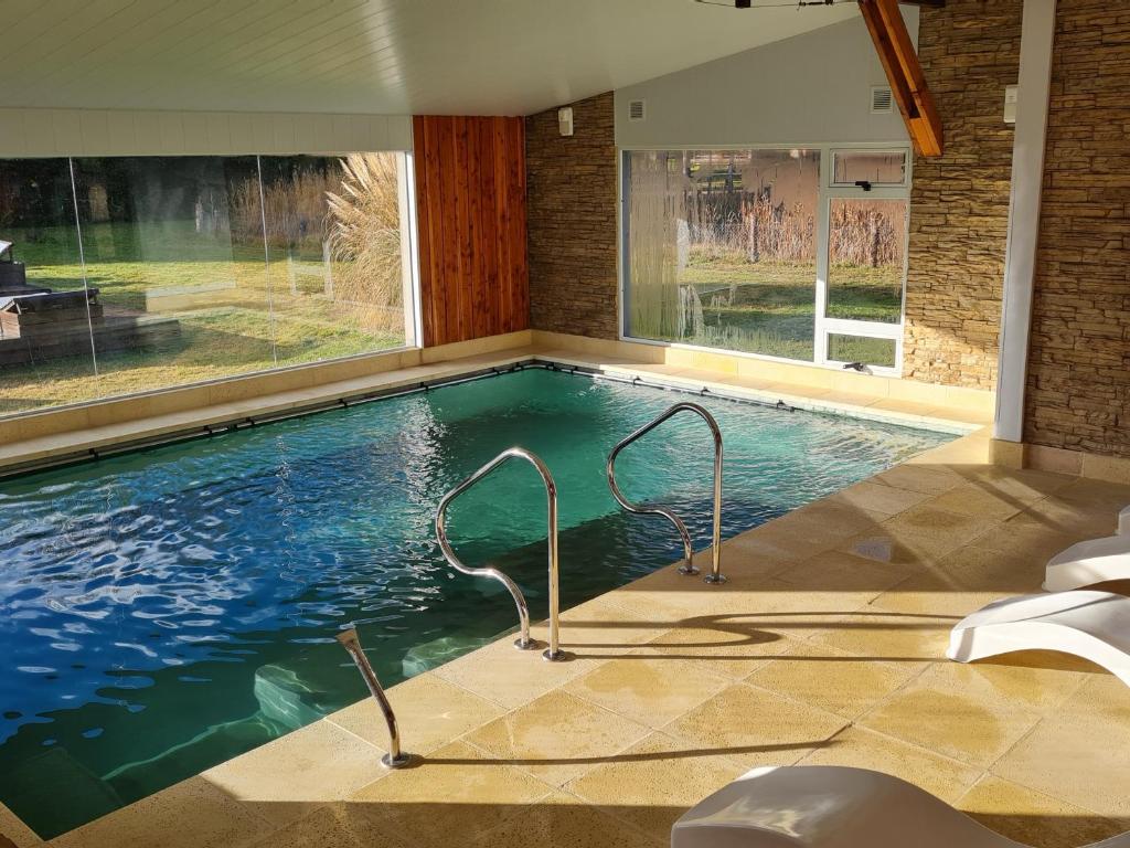 a swimming pool with two chairs in a house at Las Nubes in El Bolsón