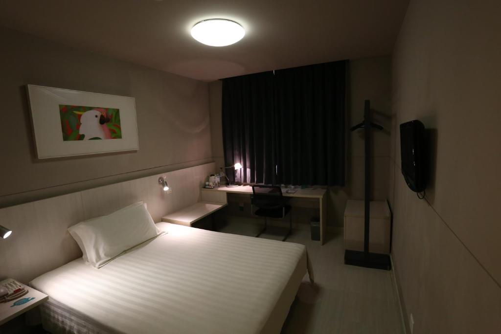 a bedroom with a bed and a desk and a window at Jinjiang Inn Huainan Railway Station Middle Shungeng Road in Huainan