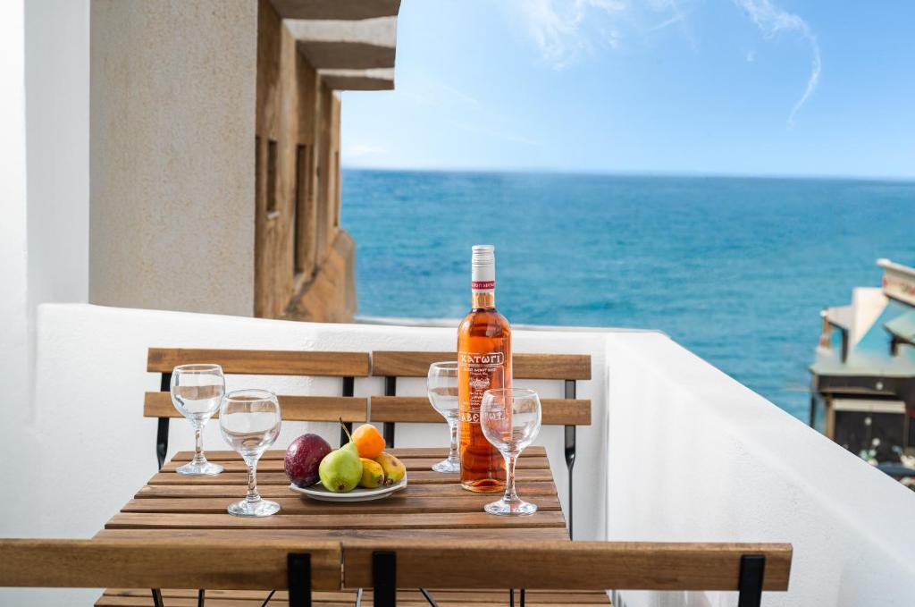 a table with a bottle of wine and a bowl of fruit at Makas Beach Suites Seafront Sea View in Hersonissos in Hersonissos