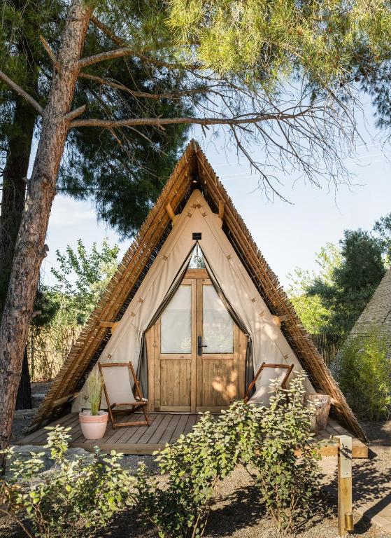 a thatch roofed yurt with a porch and a door at Ergon Beach House Nikiti in Nikiti