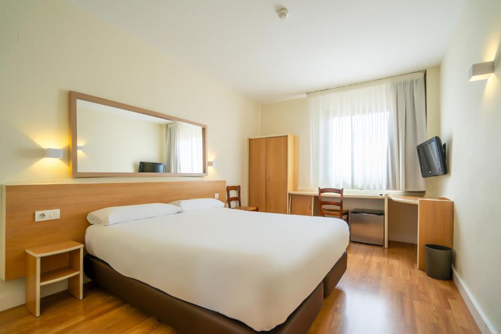 Habitación de hotel con cama grande y espejo en Hotel YIT Ciudad de Elche, en Elche