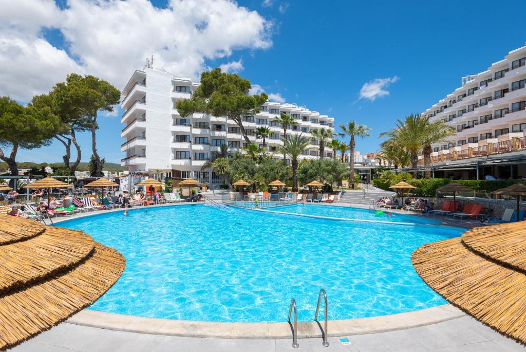 a large swimming pool with umbrellas in front of a hotel at Leonardo Royal Hotel Ibiza Santa Eulalia in Es Cana