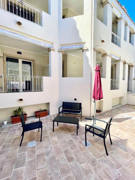 a patio with benches and an umbrella in front of a building at Domu Su Neulaghe in Villasimius