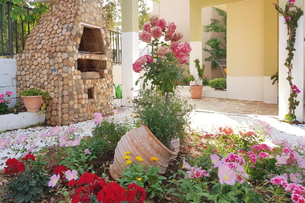 een tuin met bloemen voor een steenoven bij Marinos' Place in Skala Kallirakhis