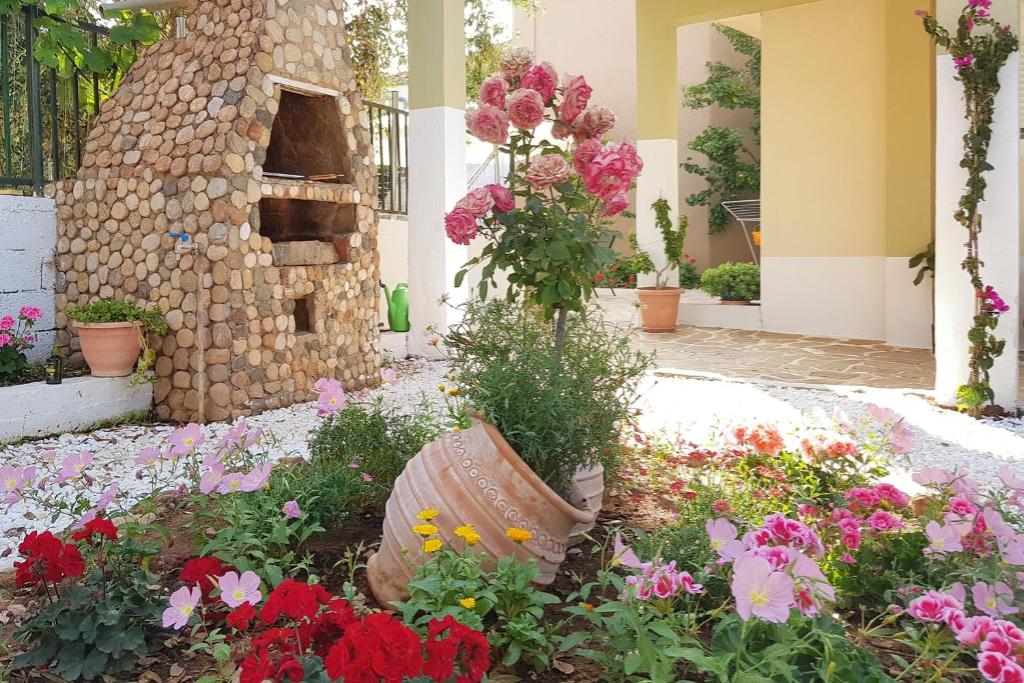a garden with flowers in front of a stone oven at Moloha in Skala Kallirakhis