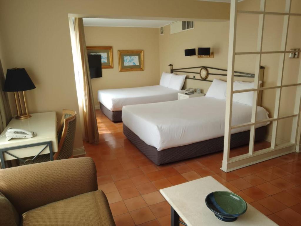 Habitación de hotel con 2 camas y sofá en Suites del Bosque Hotel, en Lima