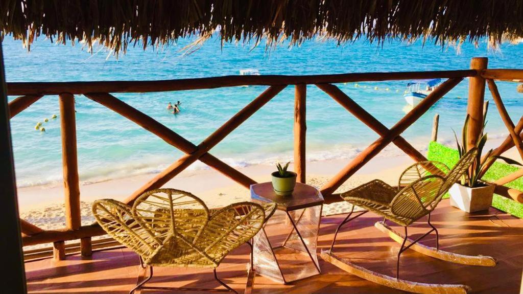 eine Terrasse mit Stühlen, einem Tisch und Strand in der Unterkunft Soy Local Barú in Barú