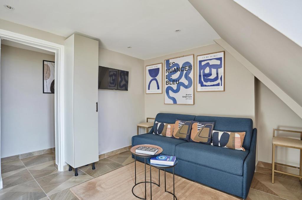 un salon avec un canapé bleu et quelques photos dans l'établissement Charming Studio Center of Paris Le Marais by Studio Prestige, à Paris