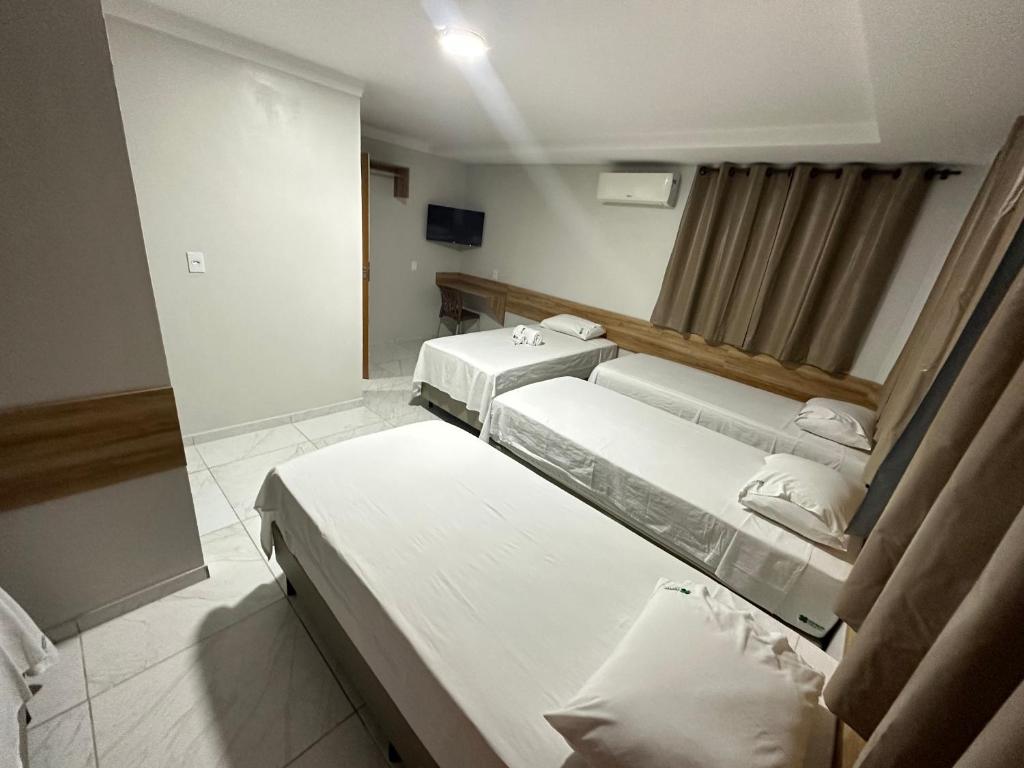 Habitación hospitalaria con 3 camas y espejo en Hotel Trevo Caruaru en Caruaru