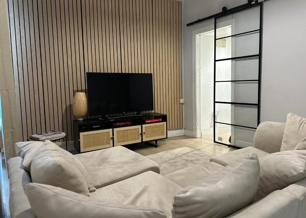 uma sala de estar com mobiliário branco e uma televisão de ecrã plano em Japandi themed London Apartment em Thornton Heath