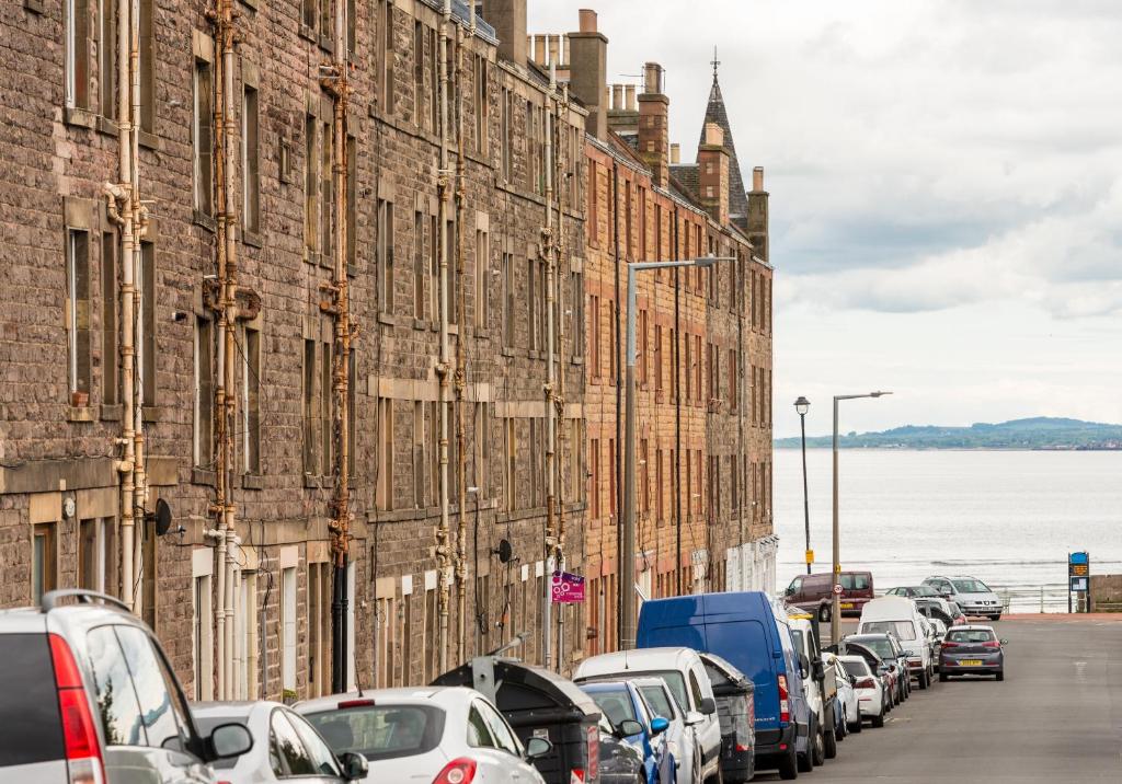 una fila de autos estacionados en una calle al lado de edificios en King's Road - 425, en Edimburgo