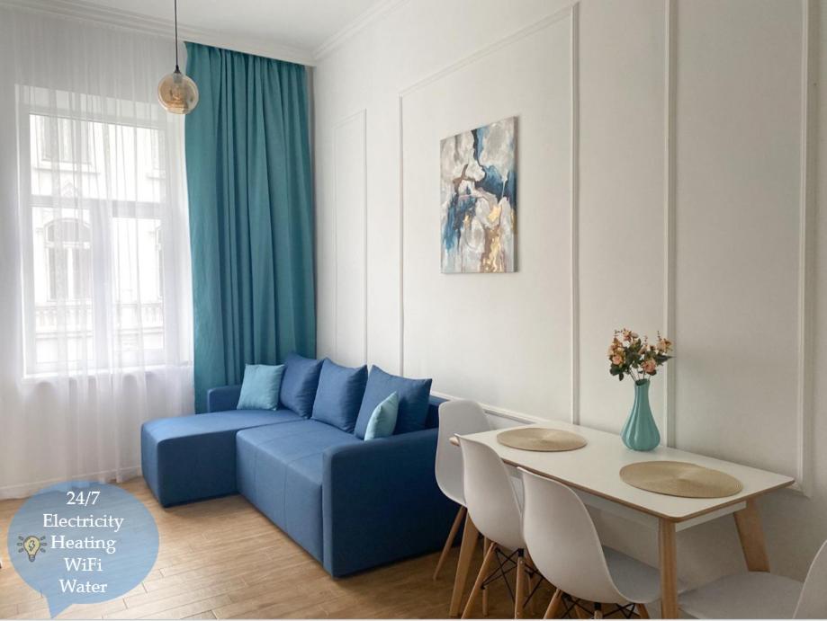 a living room with a blue couch and a table at Квартира на Огієнка 15 in Lviv