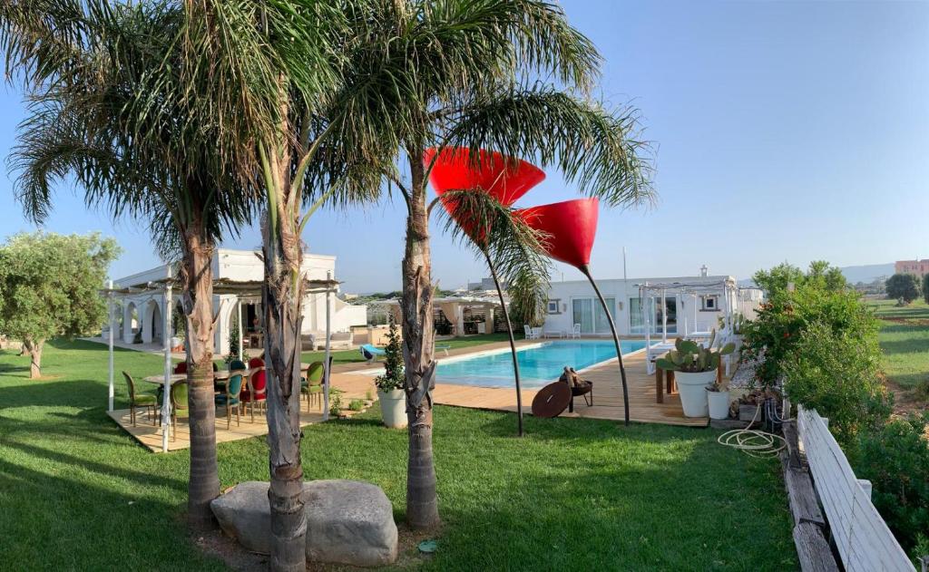 Un patio con dos palmeras y una piscina. en Villa Giuansò, en Fasano