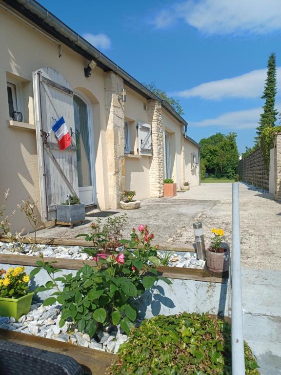 une maison avec une porte et des fleurs dans une cour dans l'établissement AU PARADIS DE BB, à Biéville-Beuville