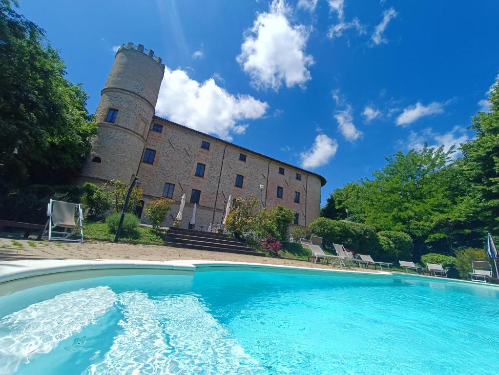 un edificio con piscina frente a un castillo en Castello di Baccaresca, en Branca