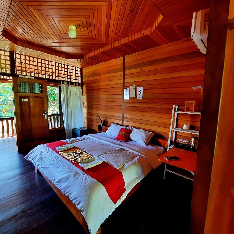 a bedroom with a large bed in a wooden room at Hotel Besar Bulan Baru Senggigi - Near Senggigi Beach in Senggigi